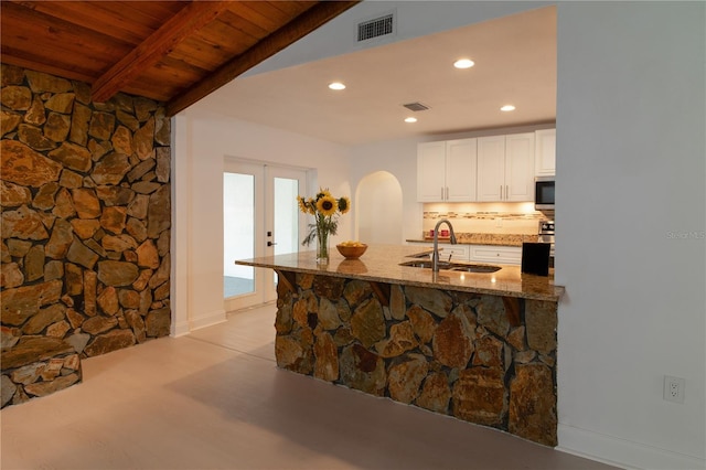 kitchen with tasteful backsplash, white cabinetry, sink, light stone countertops, and wooden ceiling