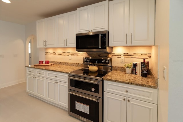 kitchen with white cabinetry, backsplash, light stone counters, and appliances with stainless steel finishes