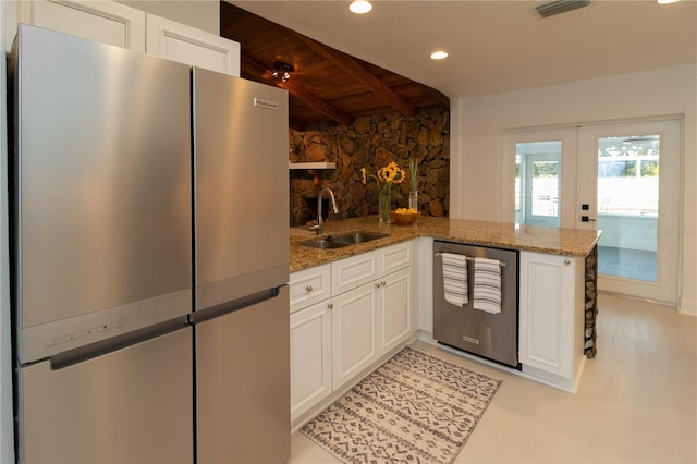 kitchen with sink, white cabinetry, stainless steel appliances, light stone countertops, and kitchen peninsula