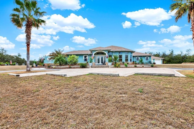 back of property featuring a garage, a lawn, and french doors