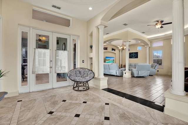 interior space with french doors, ceiling fan, ornamental molding, and decorative columns