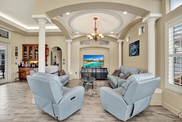 living room with ornate columns, a high ceiling, an inviting chandelier, and light hardwood / wood-style flooring