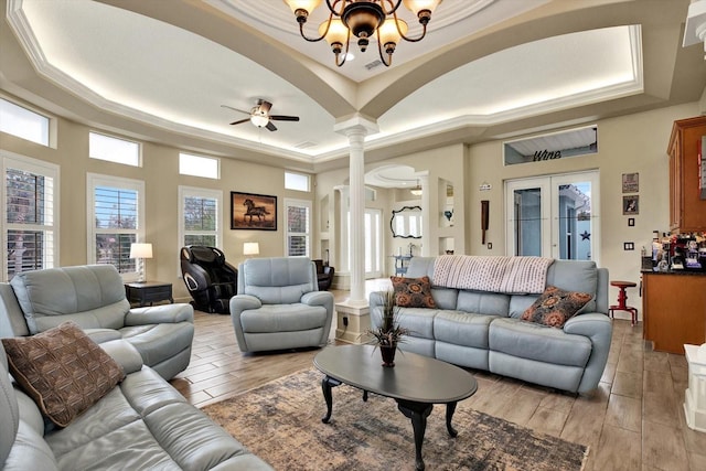 living room featuring french doors, a raised ceiling, light hardwood / wood-style floors, and ornate columns