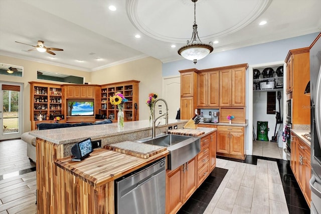 kitchen featuring a spacious island, sink, stainless steel dishwasher, pendant lighting, and light stone countertops