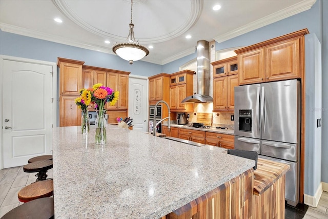 kitchen with wall chimney exhaust hood, a breakfast bar, light stone counters, stainless steel appliances, and a large island