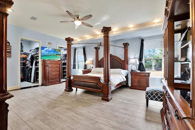 bedroom with ceiling fan, a walk in closet, and decorative columns