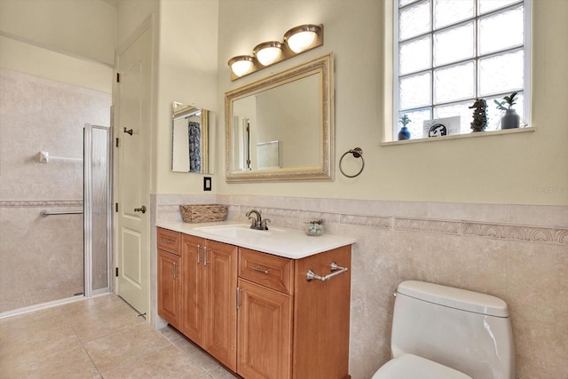 bathroom featuring vanity, tile patterned floors, tile walls, and toilet