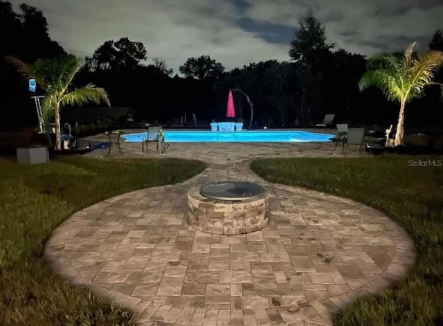 view of swimming pool featuring a yard, a fire pit, and a patio