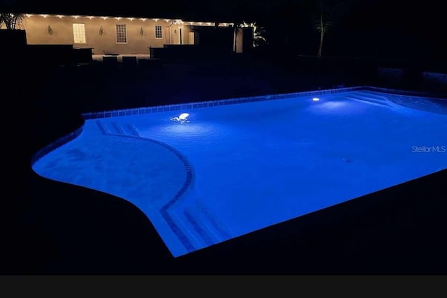 view of pool at twilight