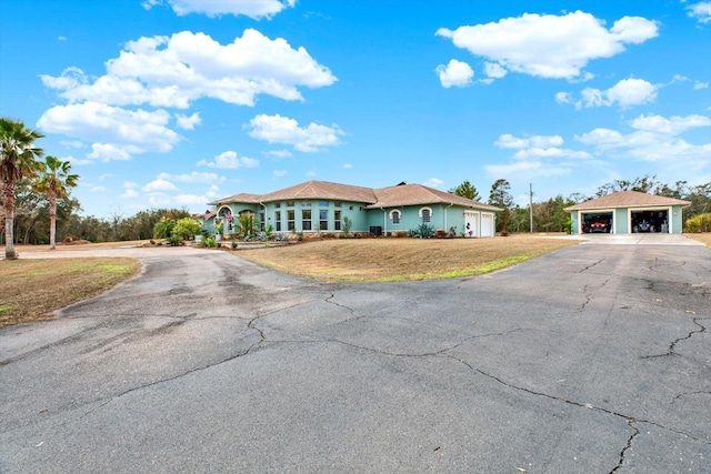 view of front of house with a garage, an outdoor structure, and a front yard