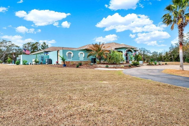 mediterranean / spanish-style home with a front lawn and central air condition unit