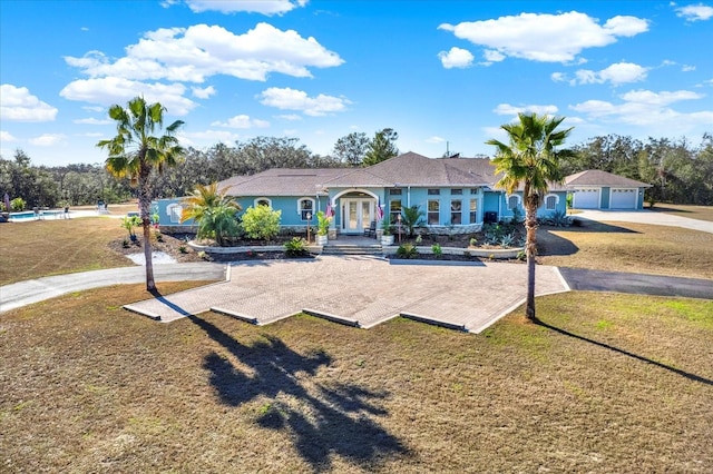 ranch-style home with a garage, french doors, and a front lawn