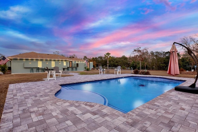 pool at dusk with a patio area