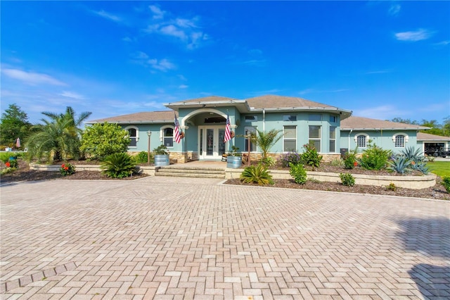 10030 Orchard Way, Spring Hill, FL 34608 - view of front of home featuring french doors, stucco siding, stone siding, and decorative driveway