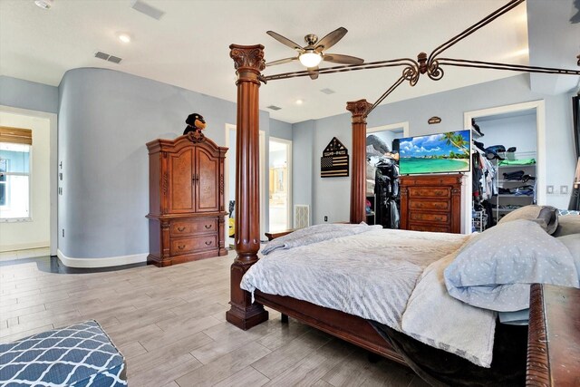 10030 Orchard Way, Spring Hill, FL 34608 - bedroom featuring light wood-type flooring, a walk in closet, ornate columns, baseboards, and a closet