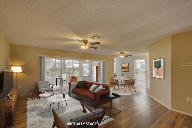 living room with hardwood / wood-style flooring, ceiling fan, and a textured ceiling