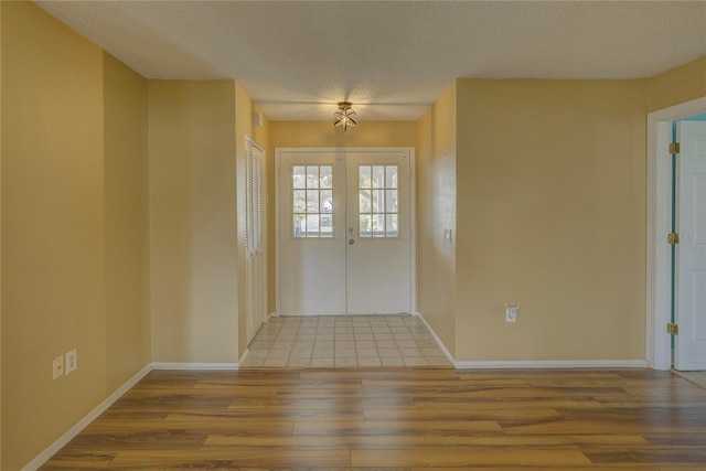 foyer with a textured ceiling, light wood-type flooring, and french doors