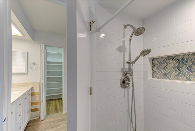 bathroom with hardwood / wood-style flooring, vanity, and tiled shower