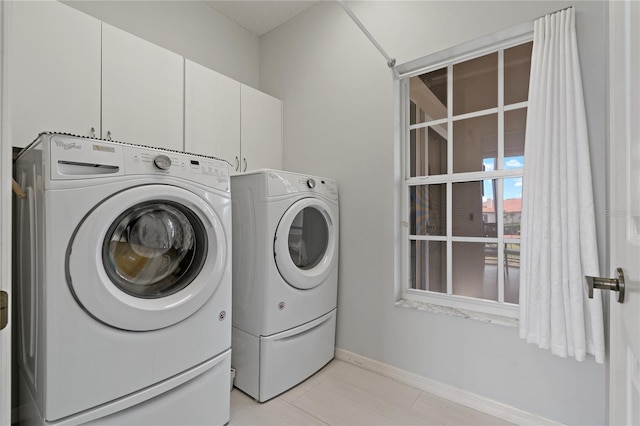 clothes washing area featuring separate washer and dryer and cabinets