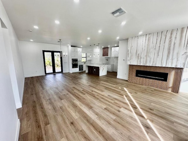 unfurnished living room with light hardwood / wood-style floors and french doors