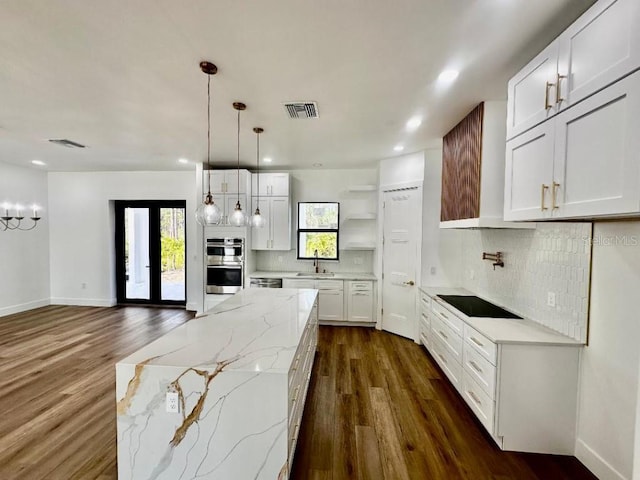 kitchen with white cabinetry, sink, light stone counters, and pendant lighting