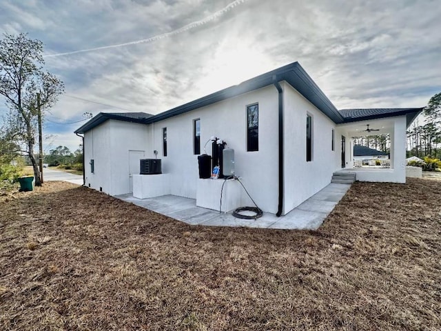 view of home's exterior with a patio, central AC unit, and ceiling fan