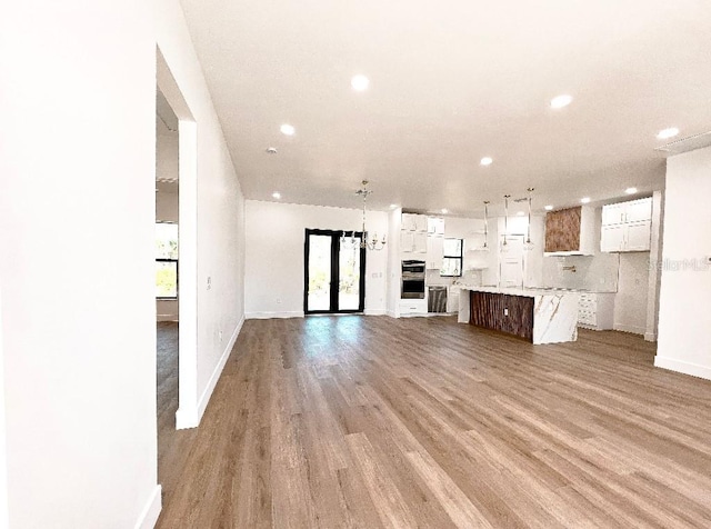 unfurnished living room featuring light wood-type flooring, baseboards, and recessed lighting