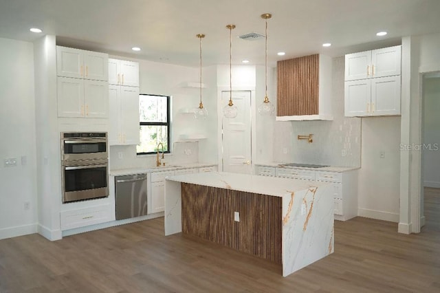 kitchen featuring hanging light fixtures, appliances with stainless steel finishes, a kitchen island, and white cabinetry