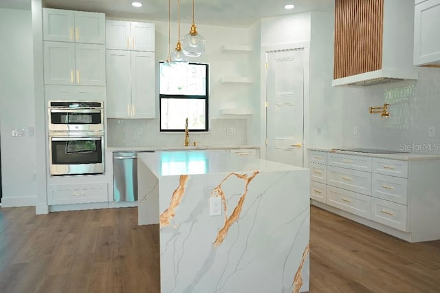 kitchen featuring pendant lighting, backsplash, double oven, white cabinetry, and wood finished floors