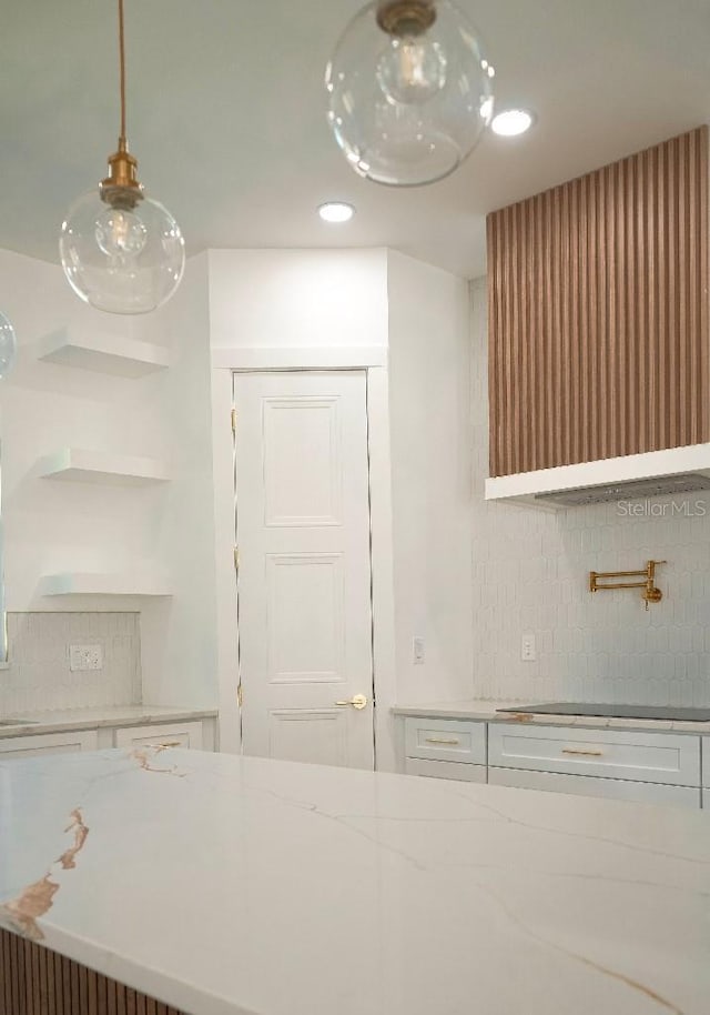 kitchen with pendant lighting, white cabinets, open shelves, and light stone countertops