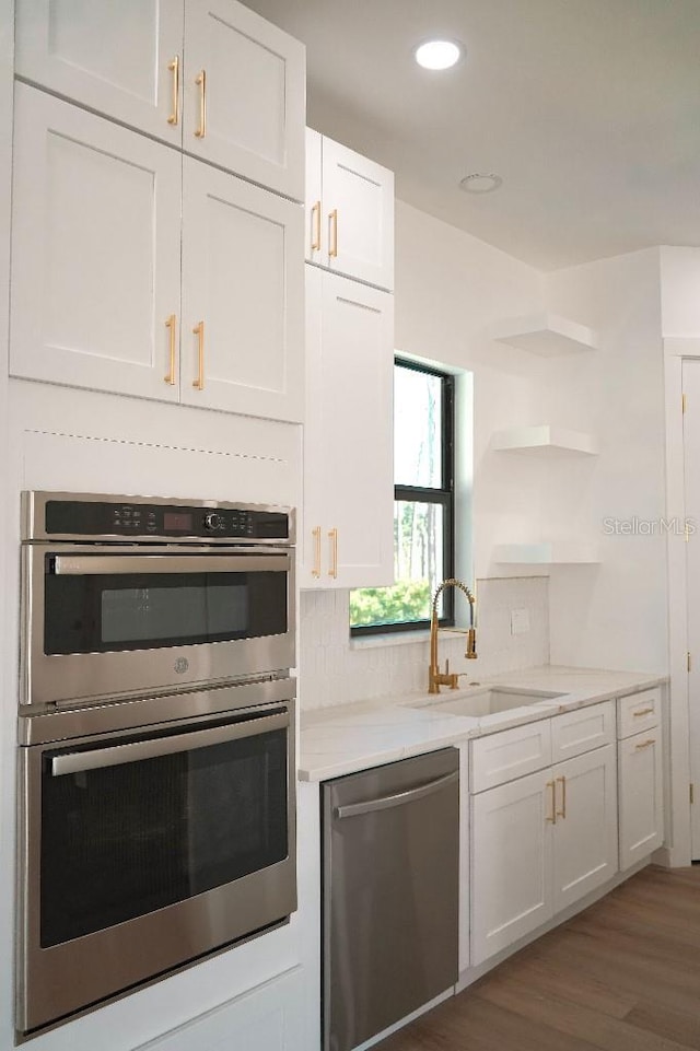 kitchen featuring open shelves, appliances with stainless steel finishes, white cabinets, and a sink