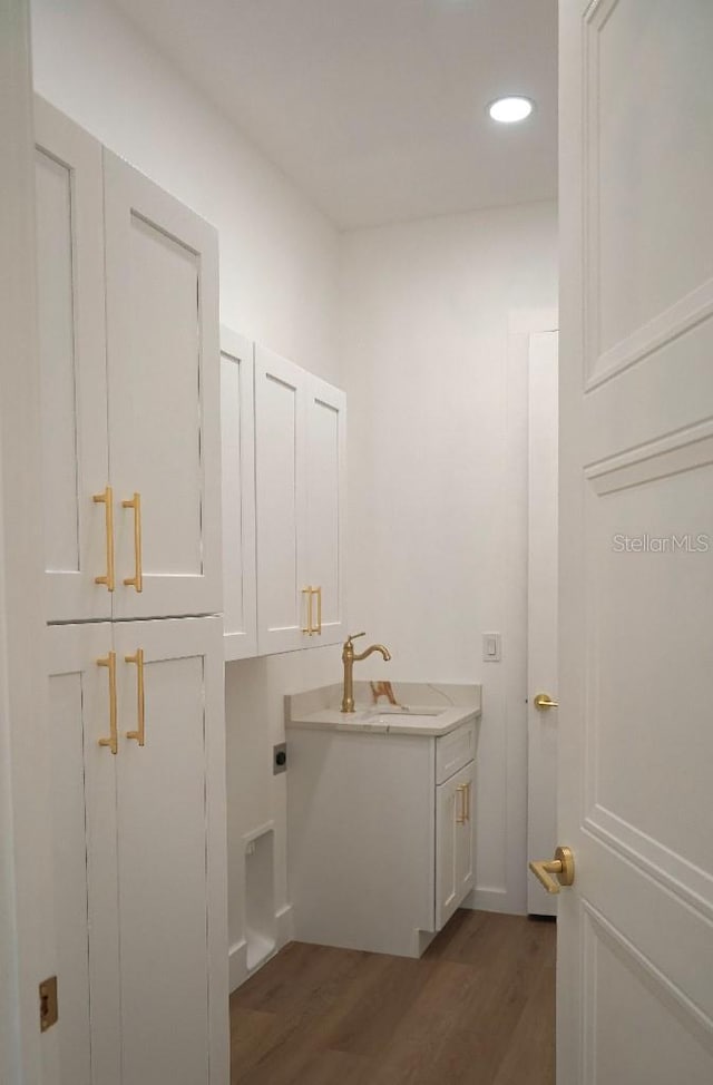 bathroom featuring recessed lighting, a sink, and wood finished floors