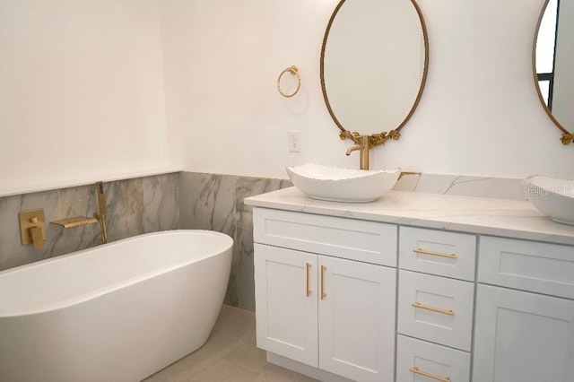 full bath featuring a freestanding tub, tile patterned flooring, a wainscoted wall, a sink, and double vanity