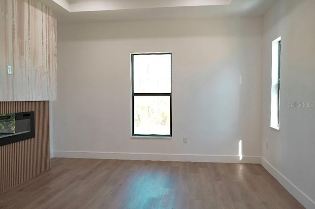 interior space featuring light wood-style floors, a glass covered fireplace, and baseboards