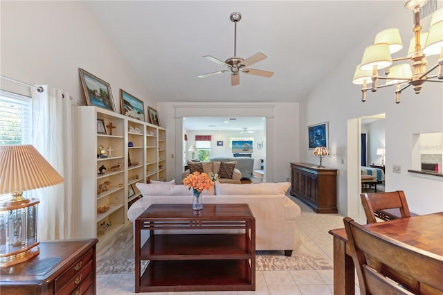 tiled living room featuring ceiling fan with notable chandelier and high vaulted ceiling