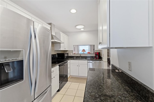 kitchen with white cabinetry, black appliances, decorative backsplash, dark stone counters, and wall chimney exhaust hood