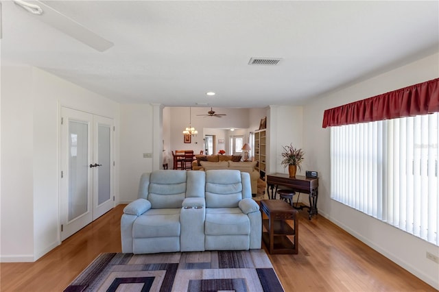 living room with hardwood / wood-style flooring, plenty of natural light, an inviting chandelier, and ornate columns