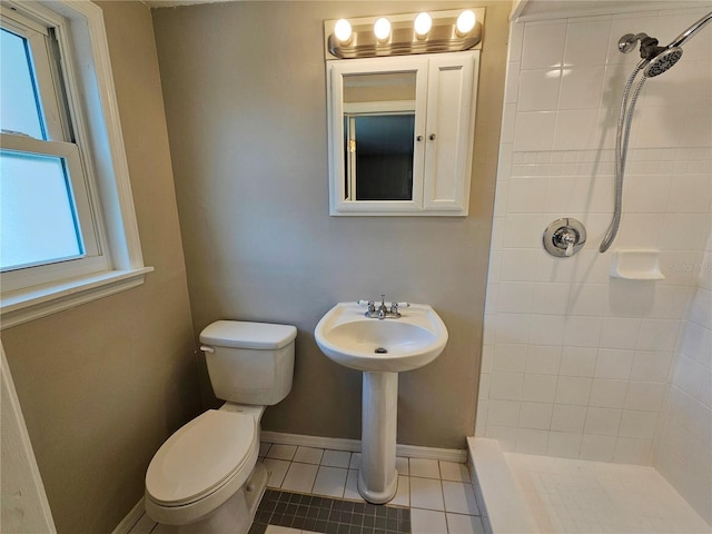 bathroom with tiled shower, toilet, and tile patterned flooring