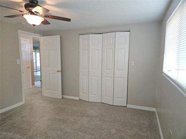 unfurnished bedroom with ceiling fan, light colored carpet, a textured ceiling, and a closet