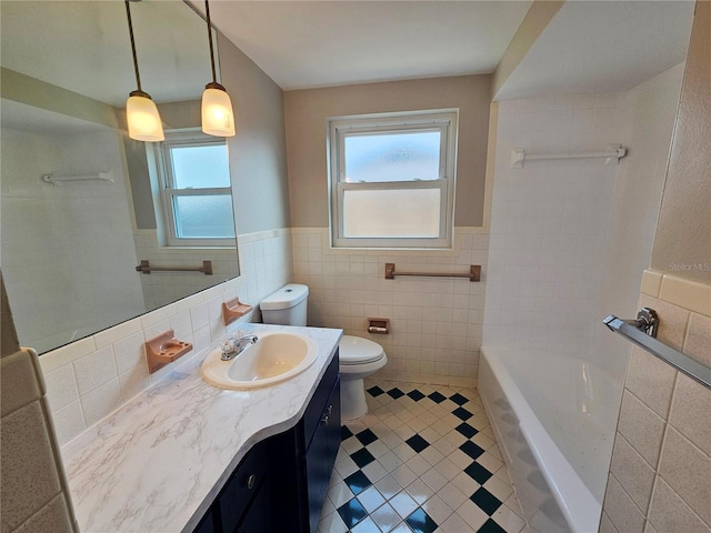 bathroom featuring vanity, a tub to relax in, tile walls, and toilet