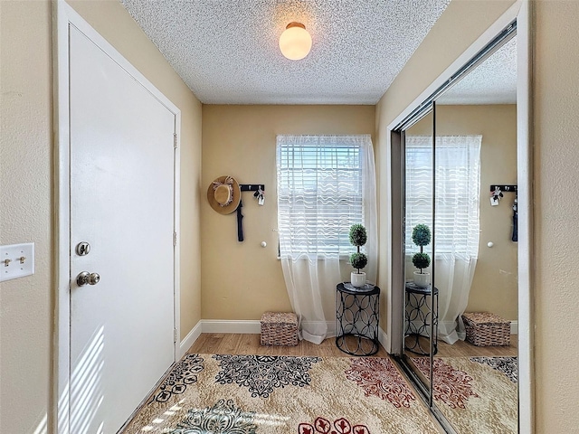 doorway to outside with light hardwood / wood-style floors and a textured ceiling