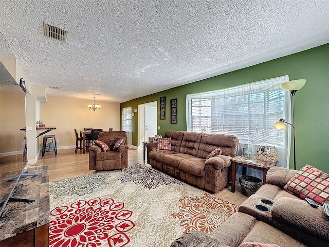 living room with a chandelier, light hardwood / wood-style floors, and a textured ceiling