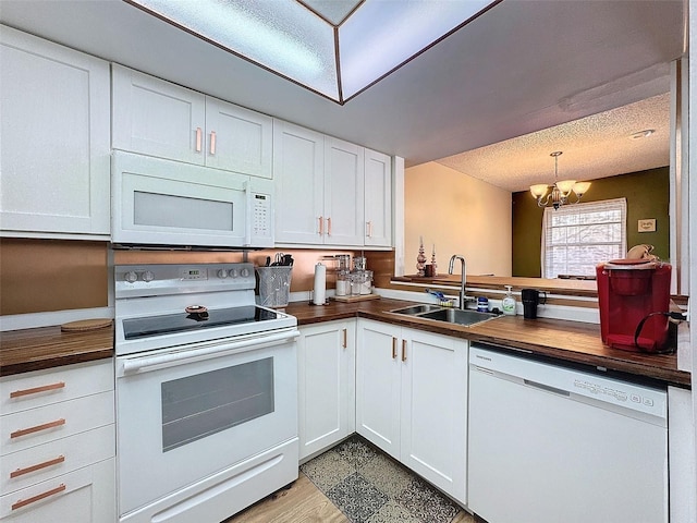 kitchen featuring sink, an inviting chandelier, white cabinets, and white appliances