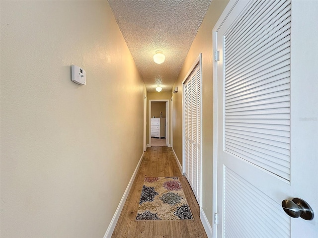 hallway with hardwood / wood-style floors and a textured ceiling