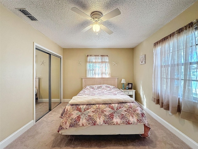 carpeted bedroom with a textured ceiling, ceiling fan, and a closet