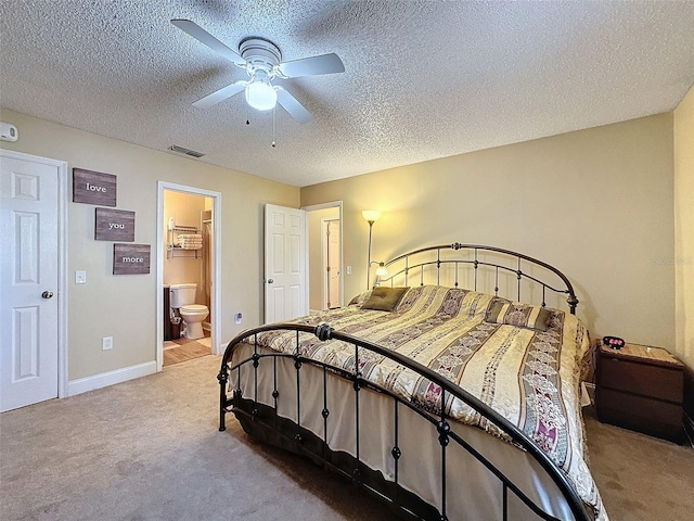 bedroom featuring ceiling fan, ensuite bathroom, carpet floors, and a textured ceiling