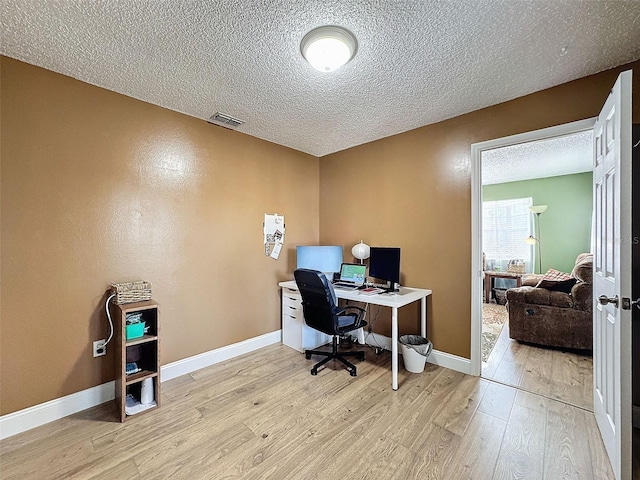 home office featuring light hardwood / wood-style flooring and a textured ceiling