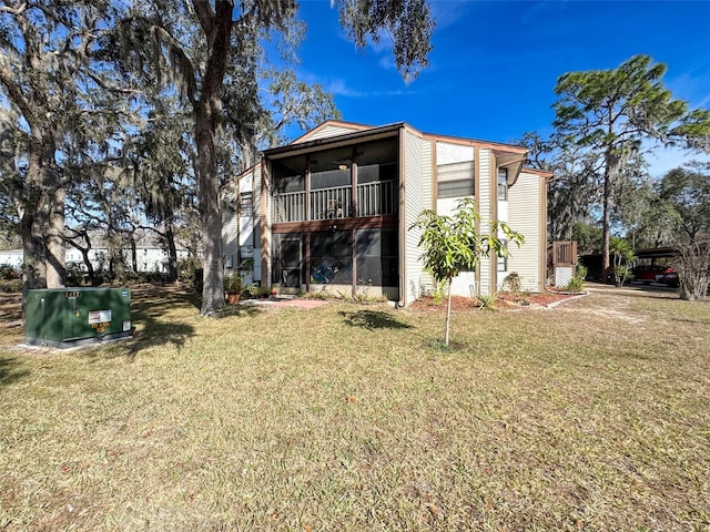 rear view of property featuring a sunroom and a lawn