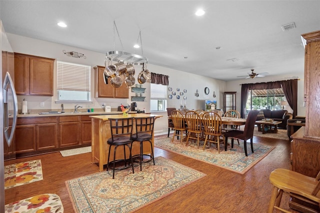 kitchen with stainless steel refrigerator, dark hardwood / wood-style flooring, sink, and a kitchen island