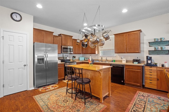 kitchen featuring a kitchen bar, sink, appliances with stainless steel finishes, dark hardwood / wood-style floors, and a kitchen island